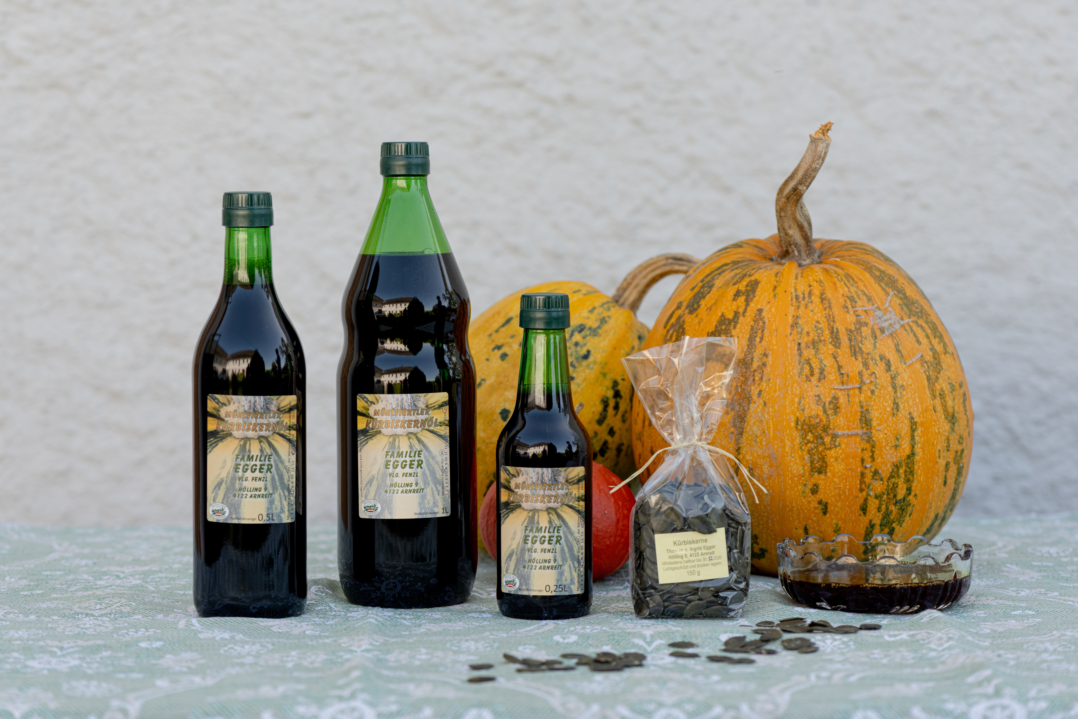 Flaschen von verschiedener Größe und Farbe und ein oranger Kürbis auf hellem Hintergrund