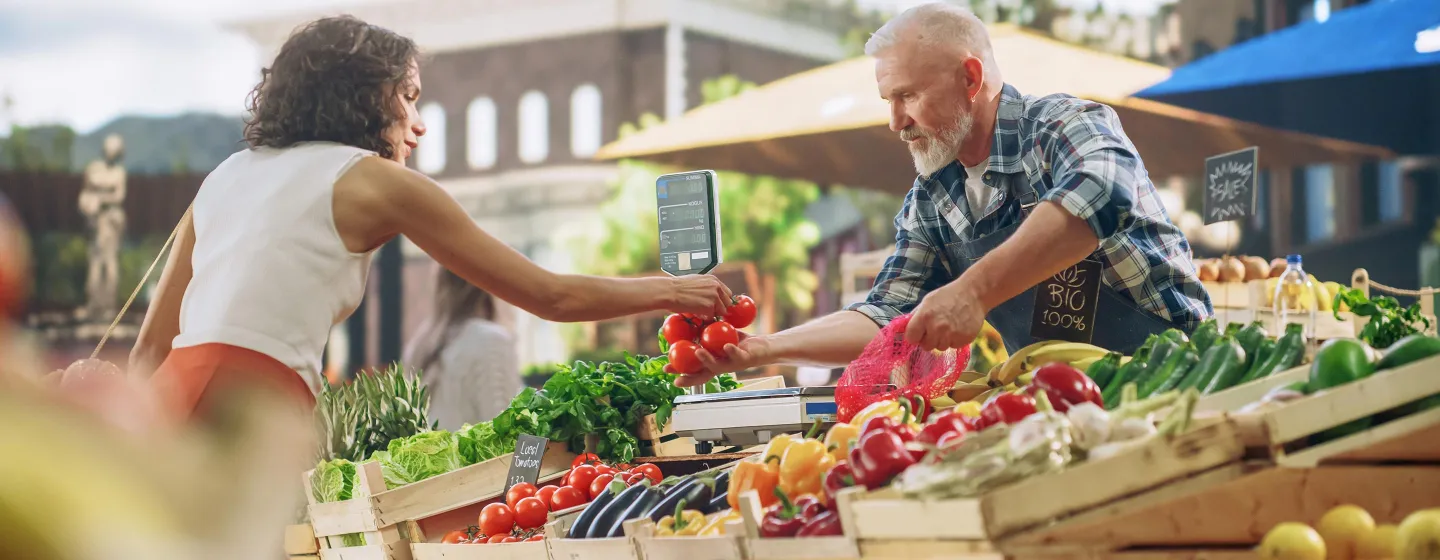 Frau kauft bei einem Verkausstand Gemüse