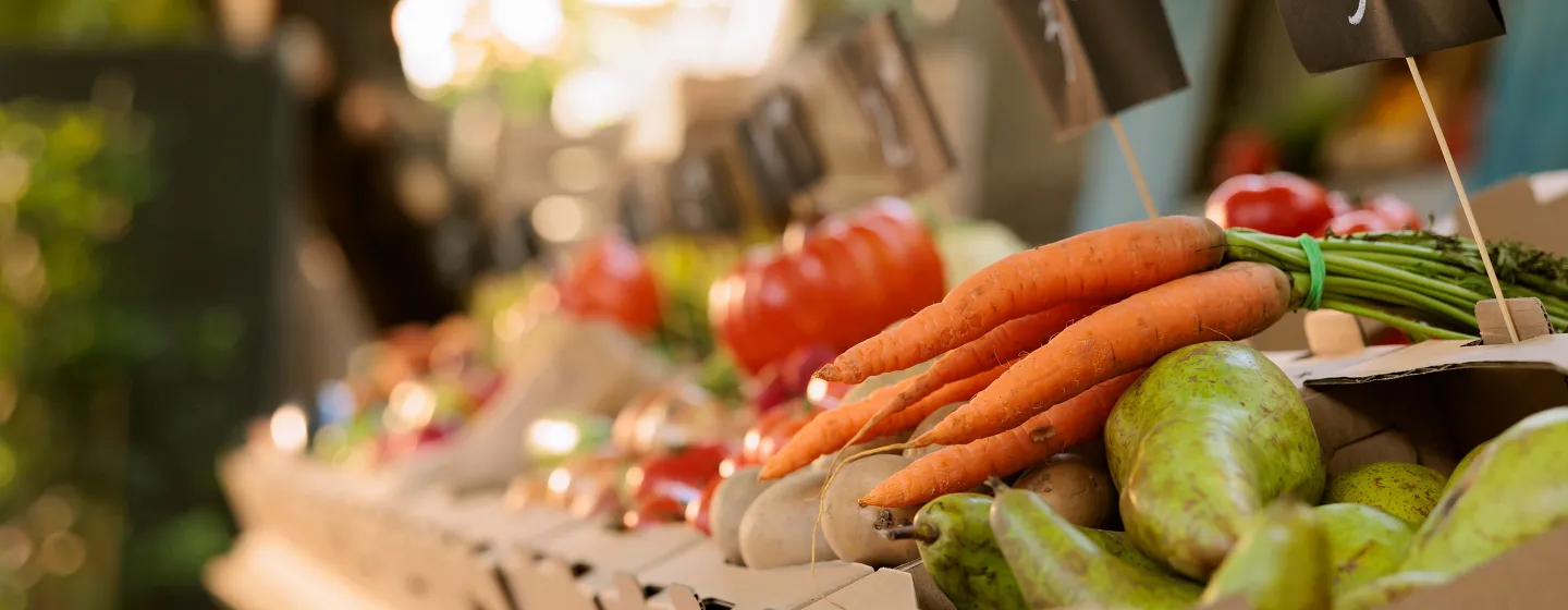 Nahaufnahme von mehreren frischen Karotten und Birnen auf einem Marktstand mit unscharfem Hintergrund.