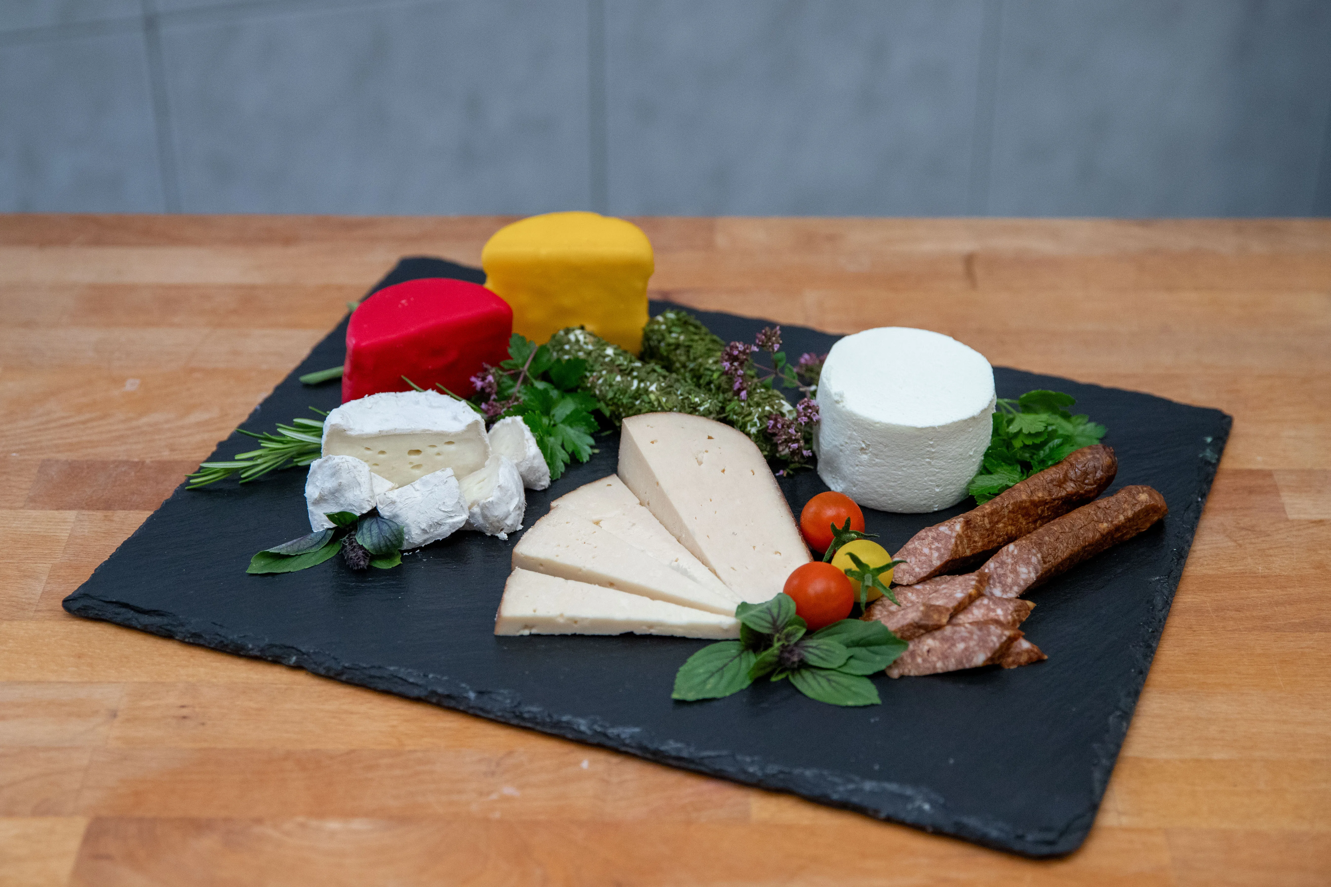 Mehrere verschieden Käsesorten auf einem schwarzen Brett auf einem braunen Tisch