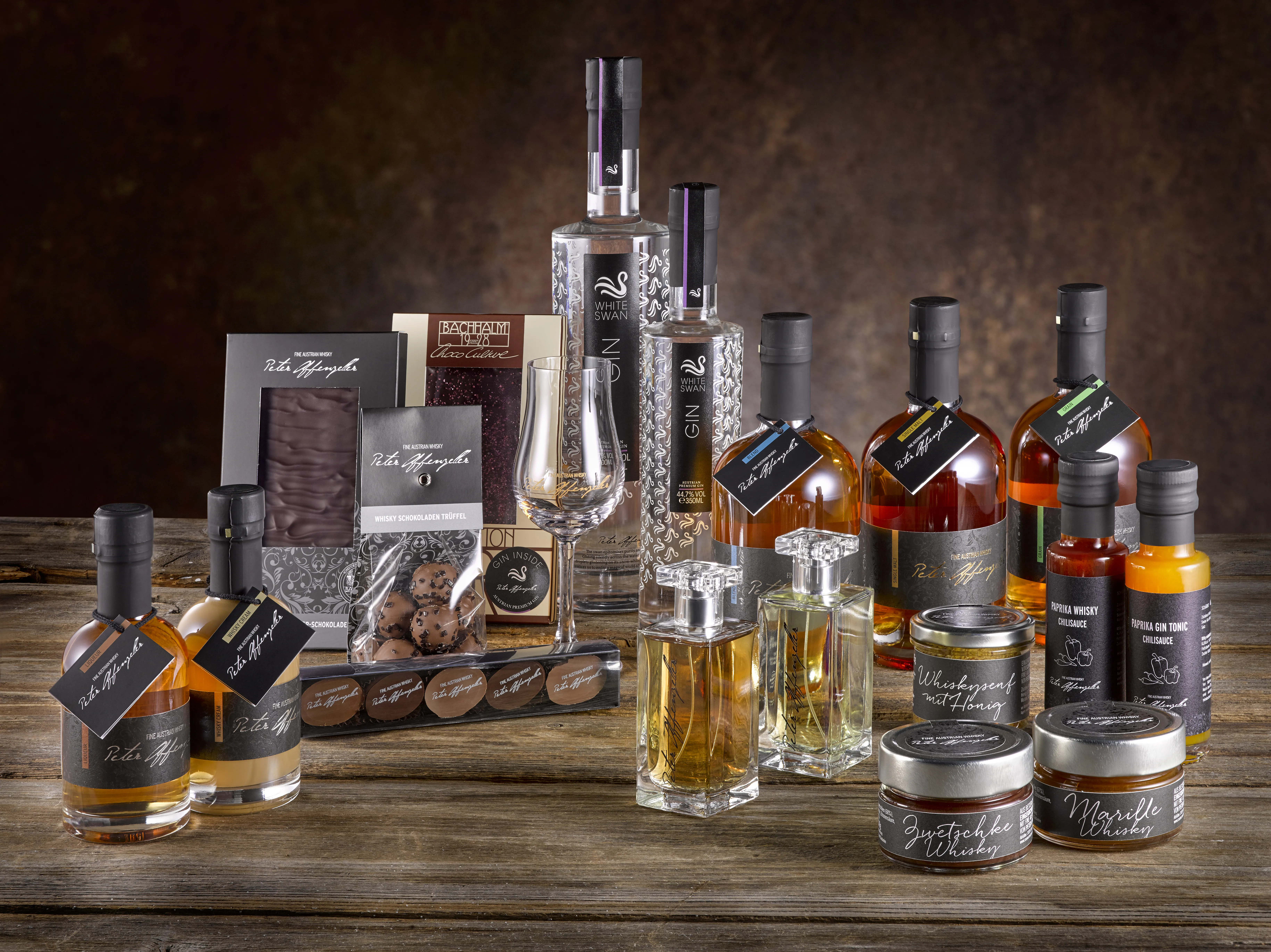 verschiedenfarbige Flaschen verschiedener Formen auf einem braunen Tisch mit dunkelbraunem Hintergrund