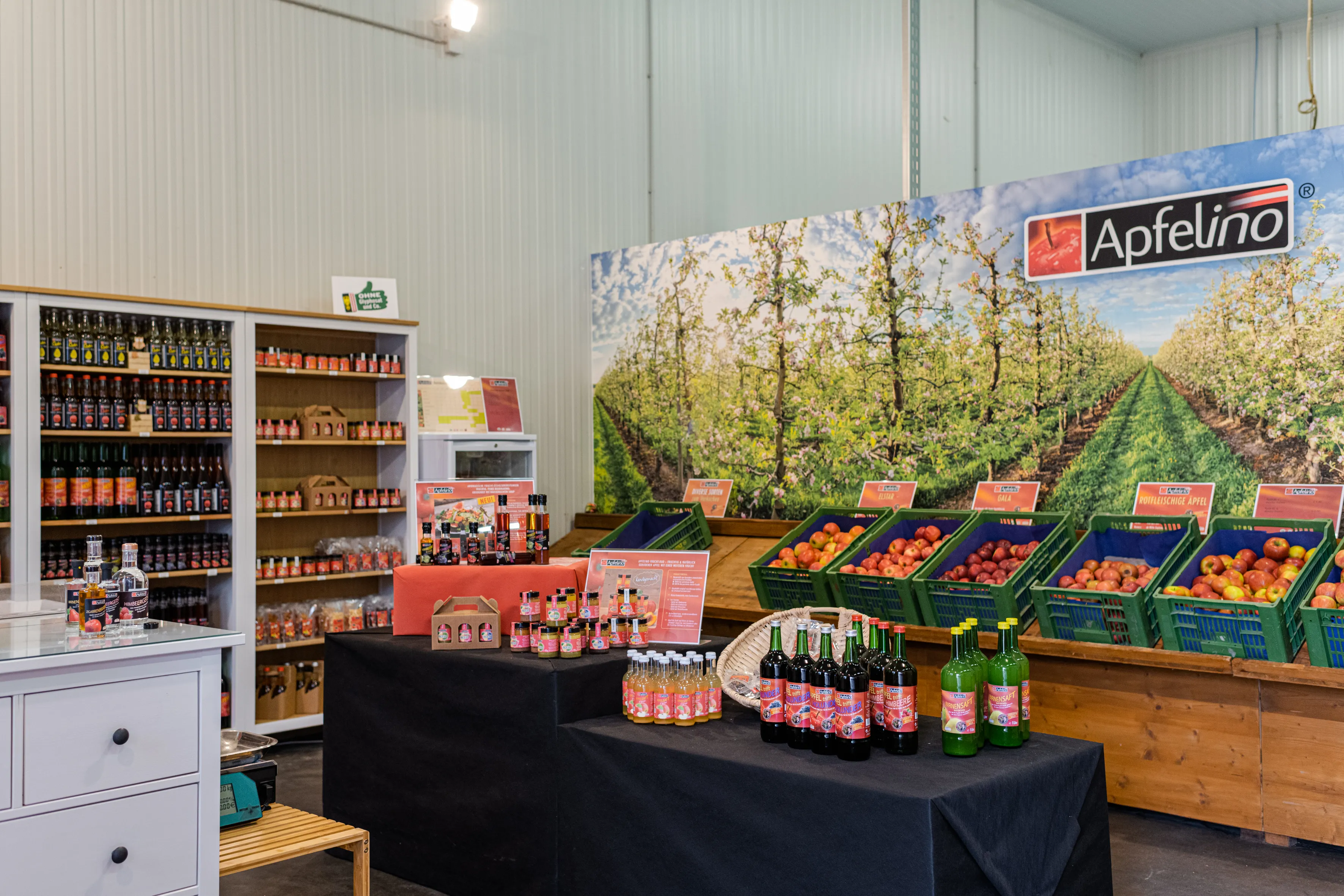 Regale, Tische und Kasterl stehen in einem Raum mit weißen Wänden; darauf verschiedene Flaschen und Produkte