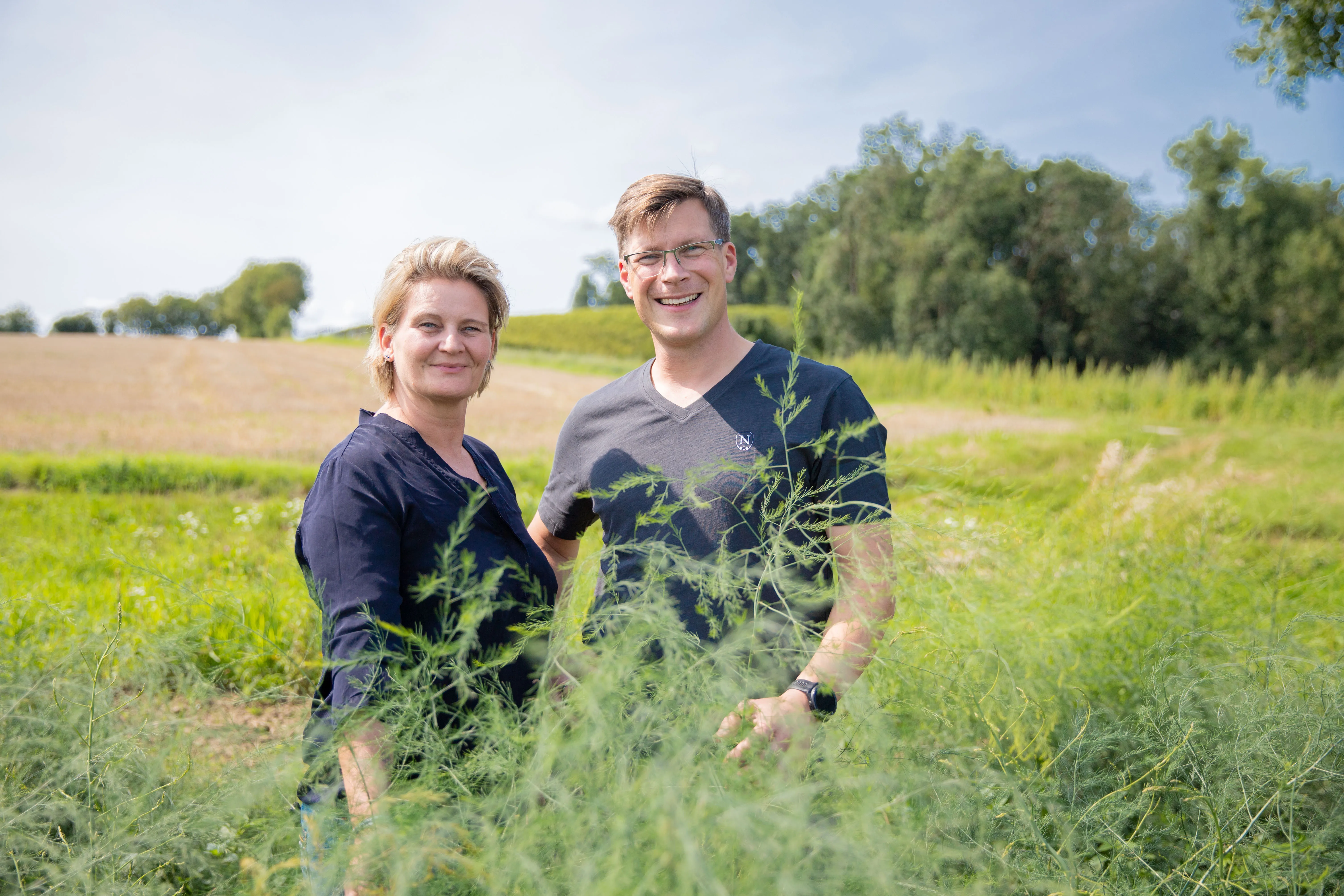 Ein Mann und eine Frau stehen auf einer grünen Wiese