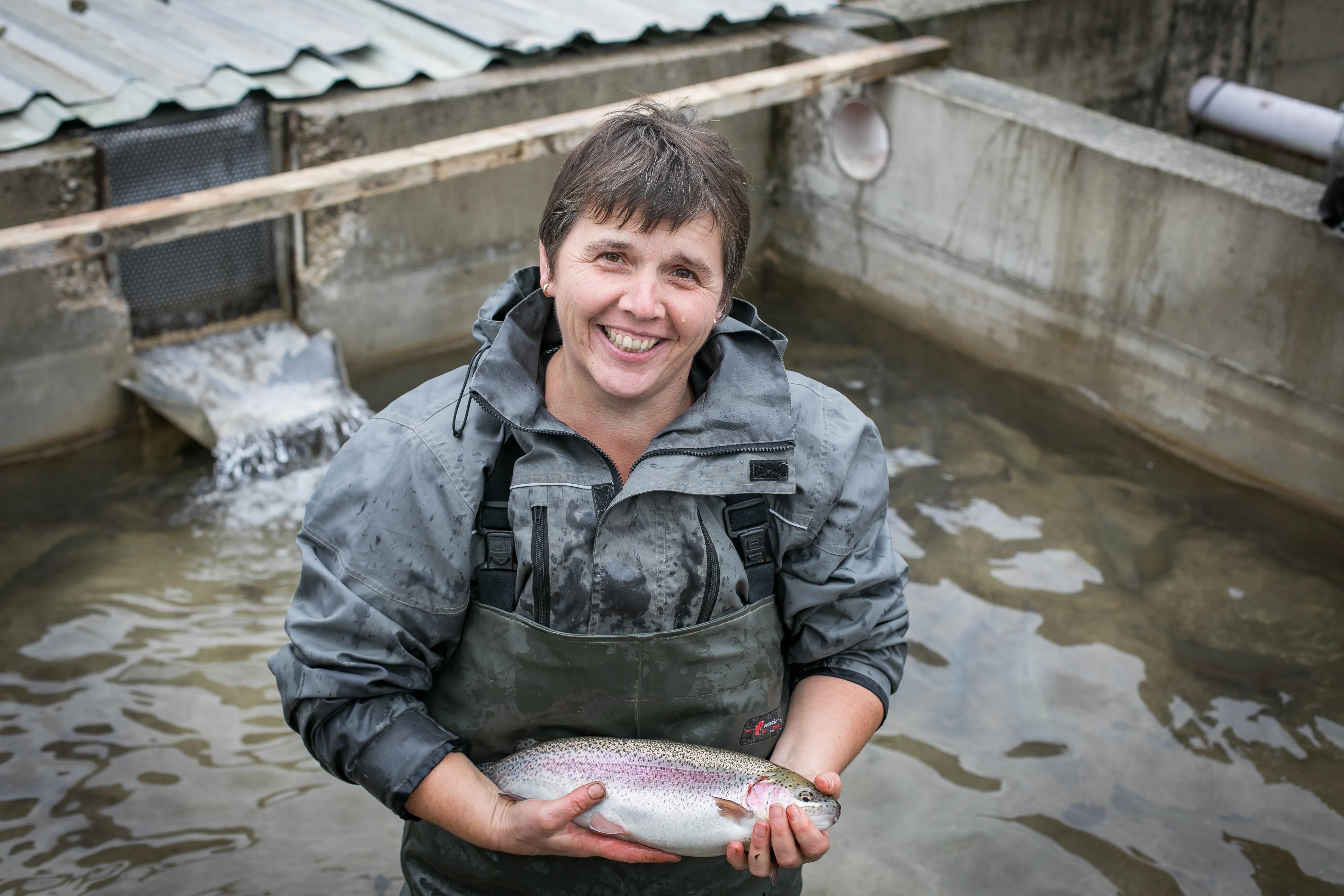 Eine Frau steht in einem Fischbecken und hält einen Fisch in der Hand