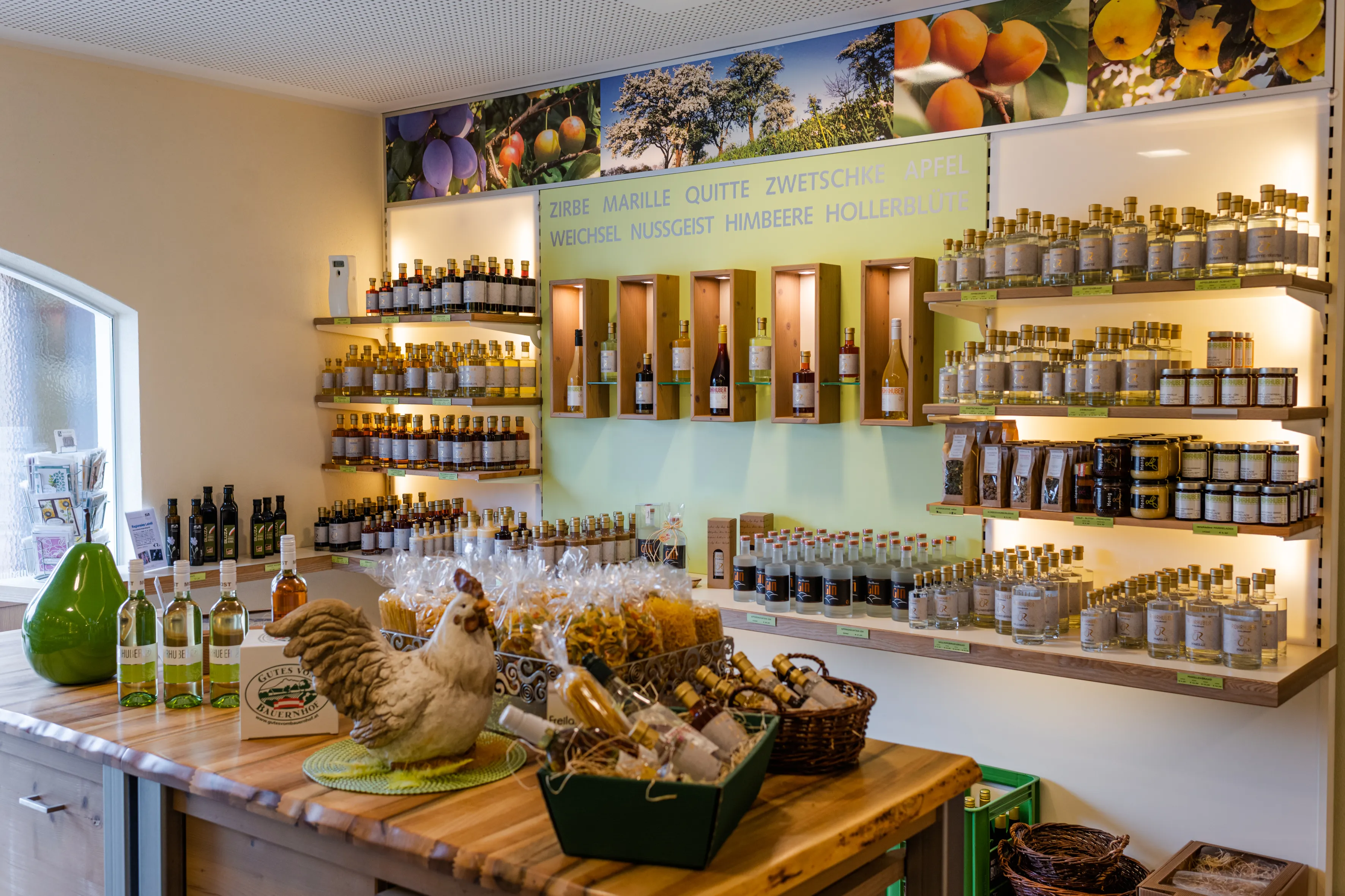 Regale an einer weißen Wand mit diversen Produkten, davor ein brauner tisch mit Geschenkkörben und ebenfalls diversen Produkten
