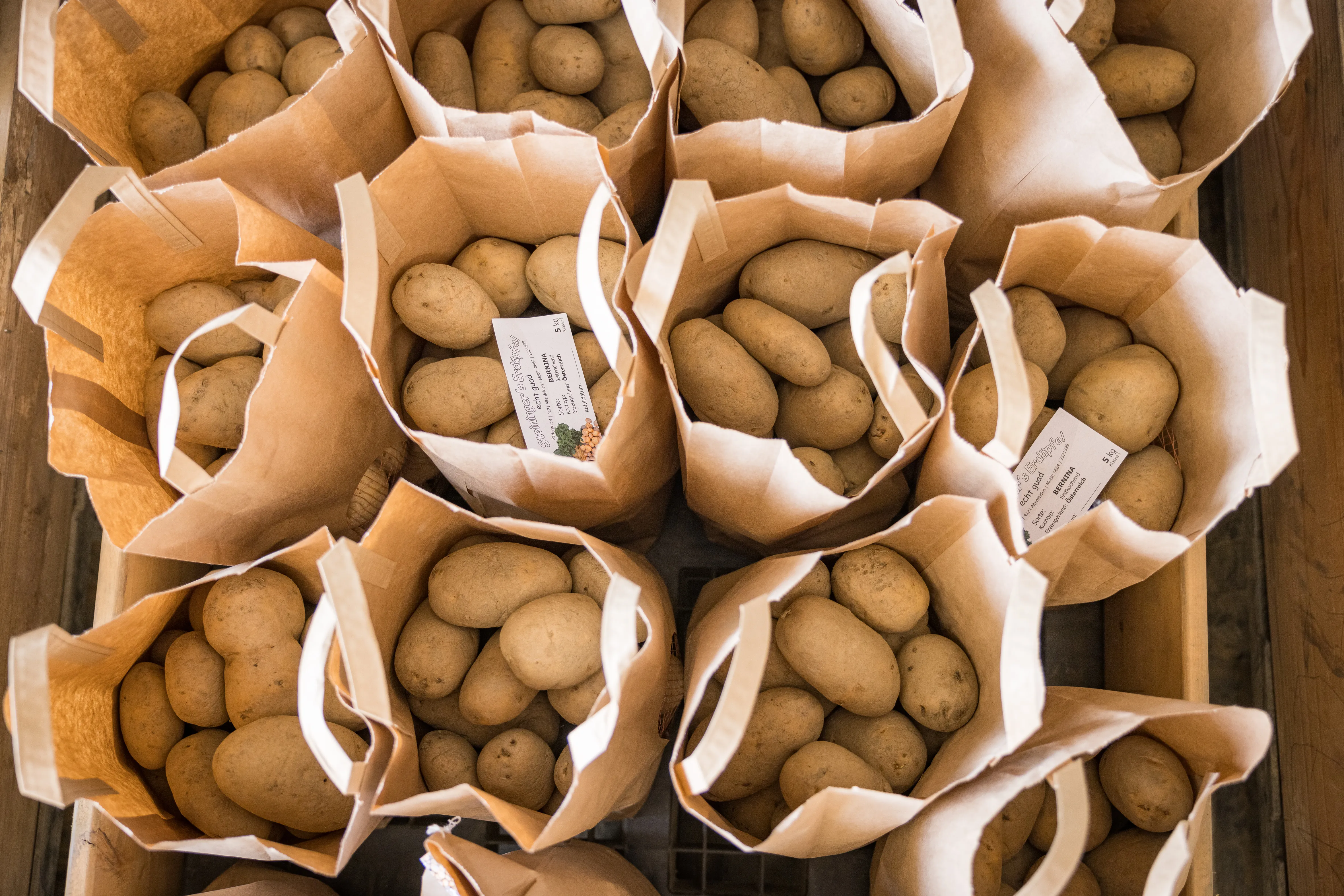 Man sieht von oben lauter braune Papiersäcke mit Kartoffeln in einer großen Kiste
