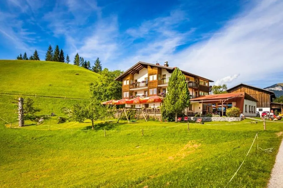 Bachrain Betriebsbild, im Vordergrund grüne Wiese und strahlend blauer Himmel