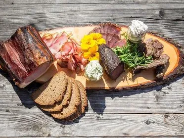 Bachrain Jausenplatte mit Schpeck, Wurst, Aufstrich und Brot auf einer Holzplatte