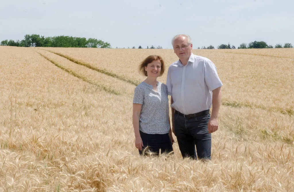 Hilde und Norbert Ecker stehen inmitten eines Waizenfeldes, dahinter grüne Bäume und Himmel
