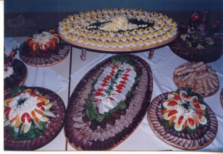 Auf einem Tisch mit weißem Tischtuch stehen verschieden große Platten mit aufgeschnitten Fleisch- und Wurstprodukten, Eiern, Aufstrichen und Garnierungen