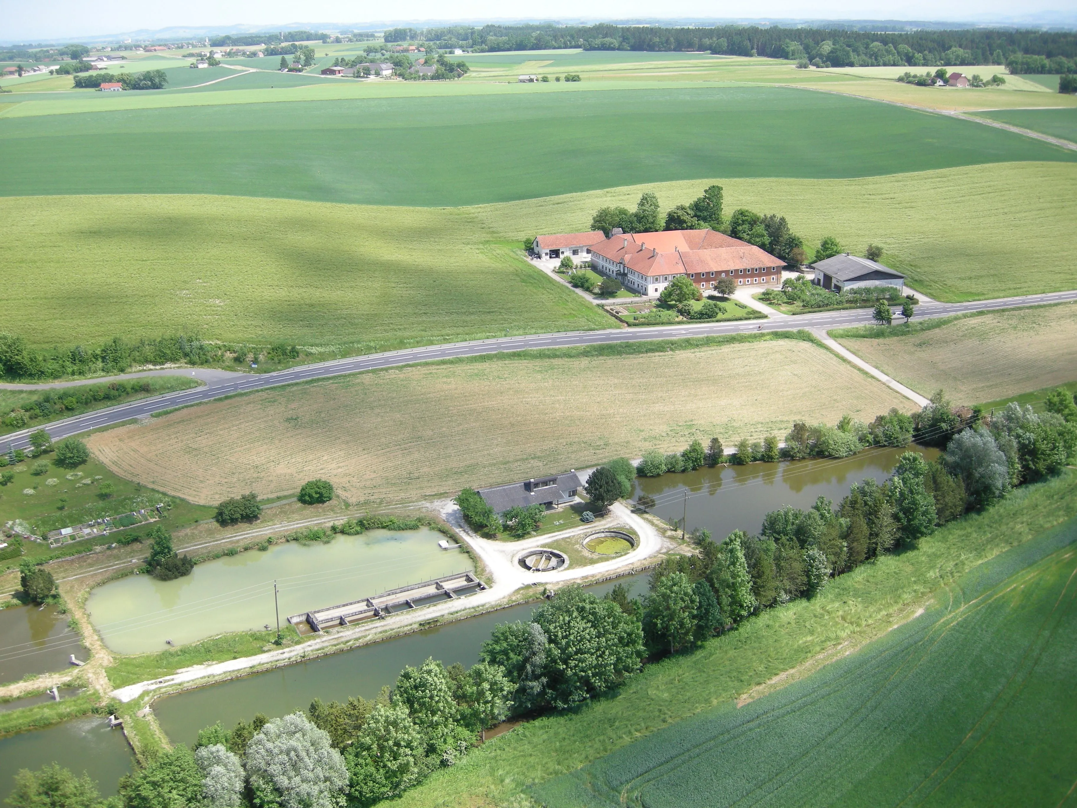 Aus der Vogelperspektive siehe man grüne Wiesen, Felder und Fischteiche. Mitten darin ein großer Bauernhof samt Nebengebäude mit rotem Dach.