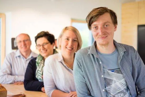 Zwei Männer und zwei Frauen stehen lehnen schräg hintereinander an einem Tresen