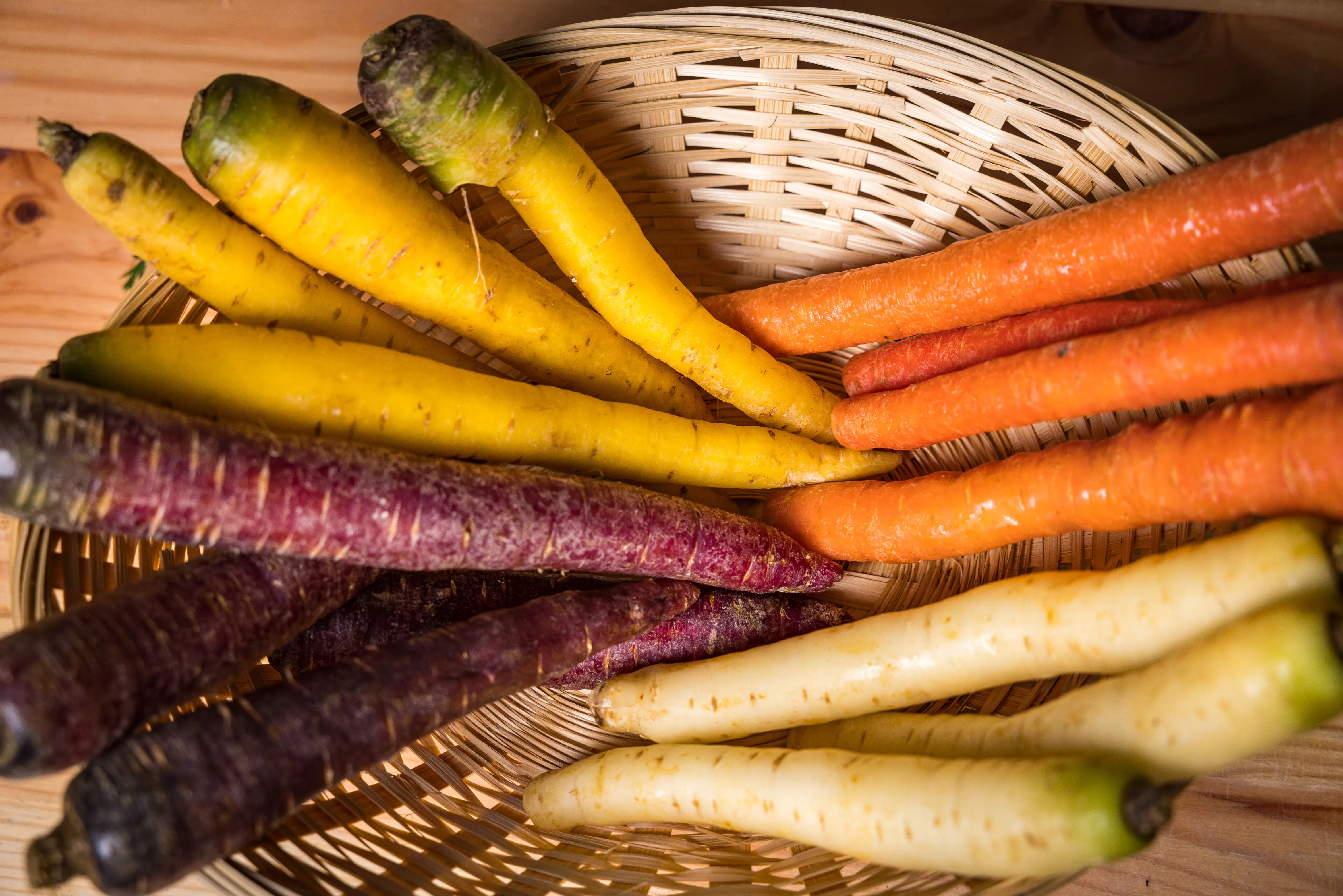 Auf dem Bild sieht man einen Korb mit verschieden farbigen Karotten bzw. Rüben.