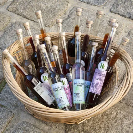 Auf Steinplatten steht ein Korb mit verschiedenen Schnaps- bzw. Likörflaschen mit verschieden färbigem Inhalt