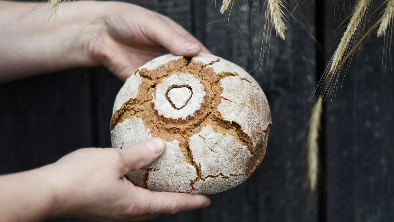 Brotlaib mit Herz in der Mitte wird gehalten