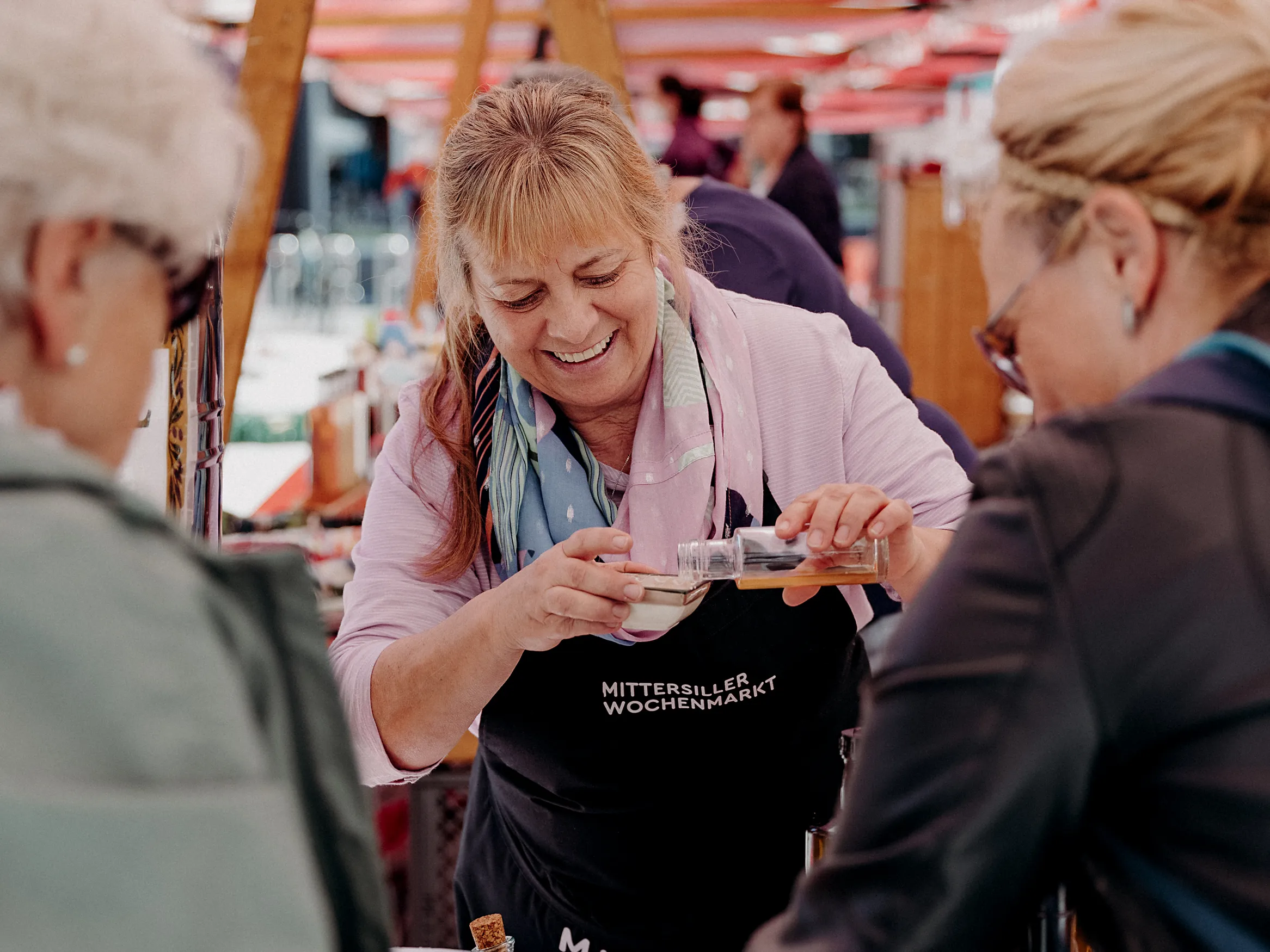 Standlerin vom Mittersiller Wochenmarkt schenkt eine Kostprobe für Kunden aus