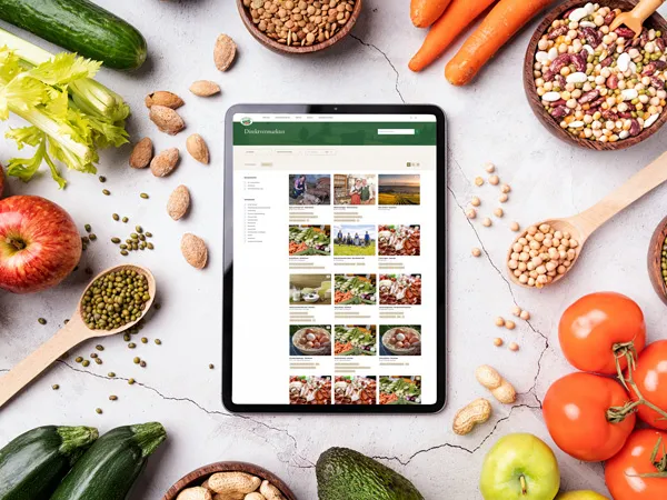 Tablet mit neuer Website liegt auf Tisch umgeben von Obst und Gemüse