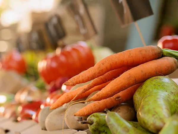 Nahaufnahme von mehreren frischen Karotten, Birnen und Tomaten auf einem Marktstand.