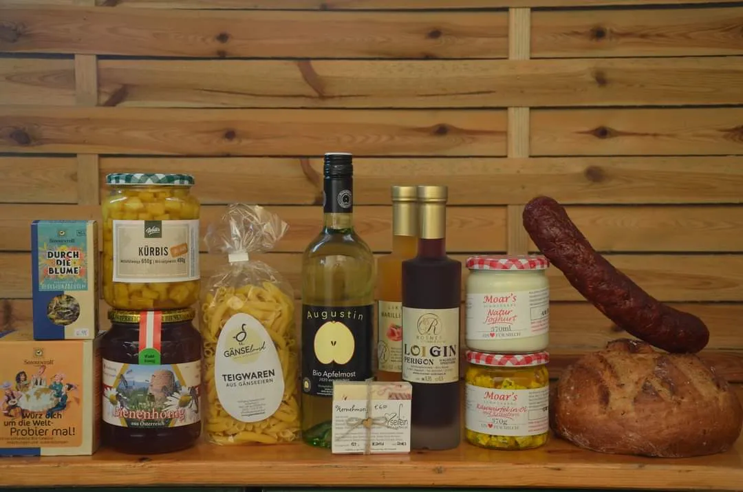 Vor einem Holzhintergrund stehen mehrere Gläser und Flaschen bzw. Sackerl mit Produkten