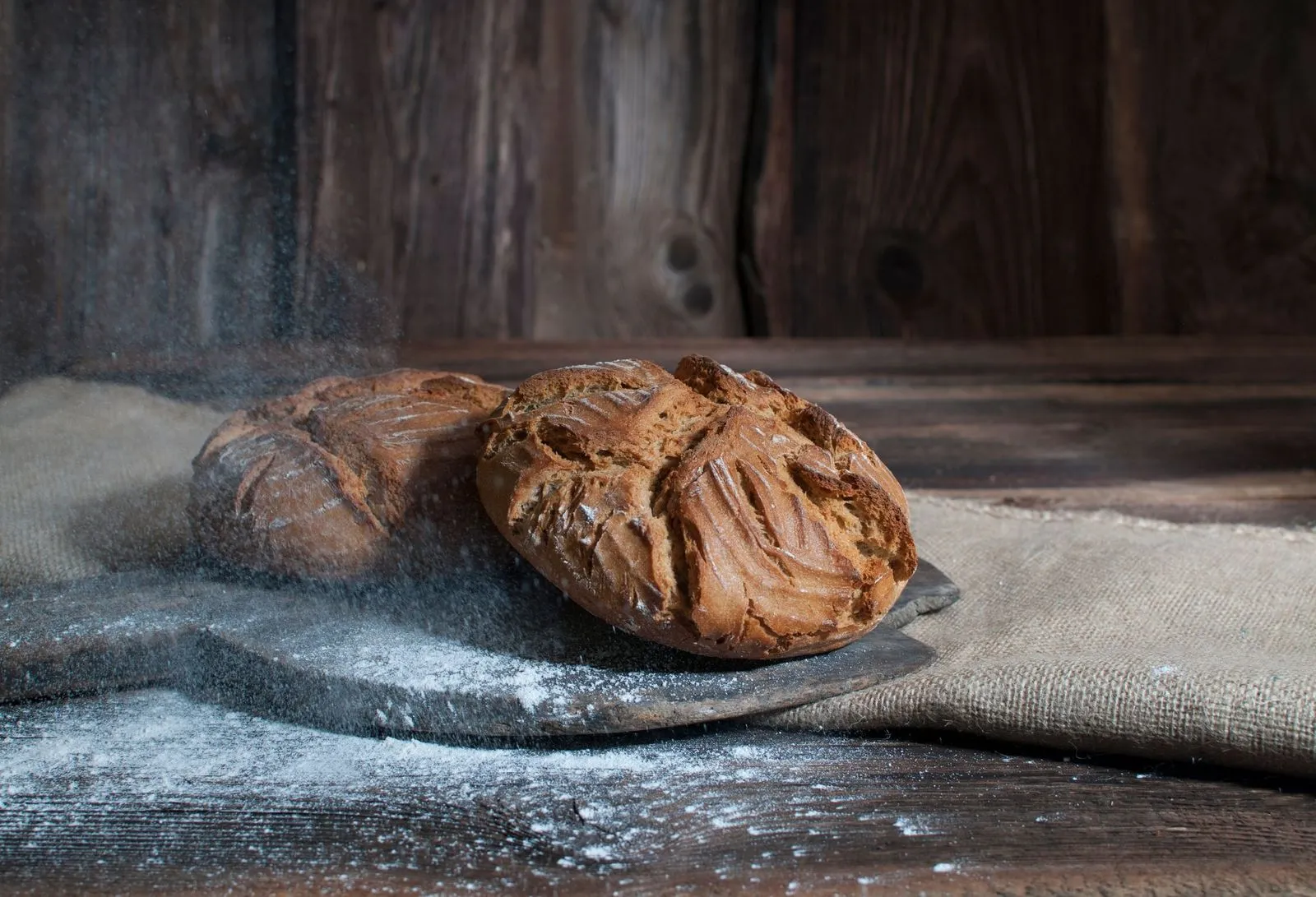 Auf dunklem Hintergrund liegt ein Brotschieber mit zwei kleinen knusprig gebackenen Brotstriezeln