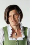 Johanna Wögerbauer mit braunen Haaren trägt grüne Trachtenbluse mit weißer Rüschenbluse darunter und eine Kette mit Anhänger.
